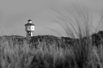 Historic Water supply Tower called “Alter Wasserturm“ on Langeoog Island Niedersachsen Germany is a museum and famous landmark. Panoramic view of tourist destination, black and white greyscale.