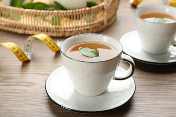 Herbal diet tea and measuring tape on wooden table