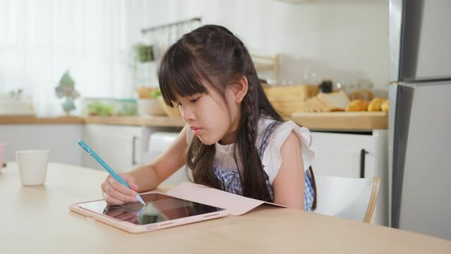 Asian young kid girl coloring and painting on tablet in living room. 