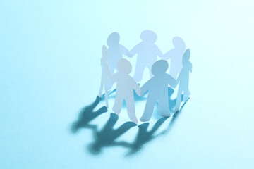 Paper people chain making circle on light blue background. Unity concept