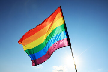 Bright LGBT flag fluttering against blue sky