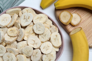 Freeze dried and fresh bananas on white wooden table, flat lay