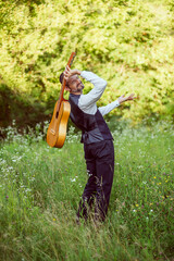 Man on a walk with a guitar and a hat