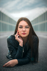 Portrait of a woman in glasses lying on a road