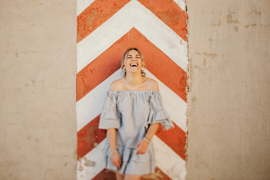 Happy woman laughing against shabby wall