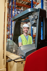 Smiling storehouse employee seated in the forklift