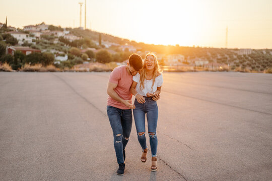 Young couple laughing together on street at dusk