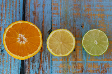 Top view of citrus fruits cut in half placed on blue aged wooden table