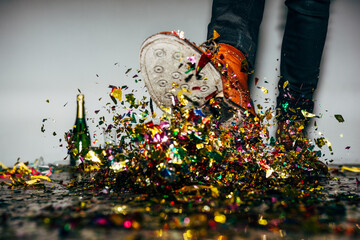 Faceless man in stylish boots kicking pile of confetti during party