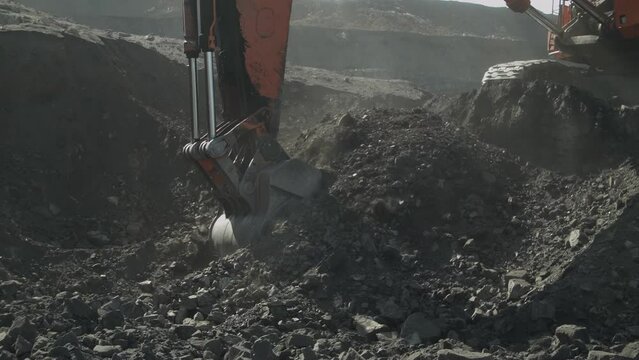 Bucket of mining excavator scoops up coal from deposit, close up view. Huge truck Loading, fuel industry.