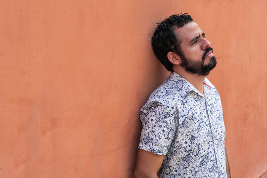 Unhappy ethnic man near wall in city