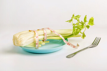 Fresh celery, measuring tape, plate, fork, diet, overweight, weight loss concept, white background, health