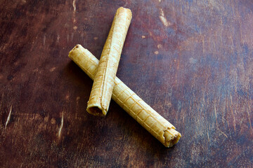 Fototapeta premium Crispy wafer sticks rolls lie on top of wooden kitchen table.