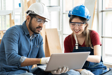 Man and woman carpenter working using laptop computer checking wood in the wood workshop. Group of carpenter worker works at the carpentry shop