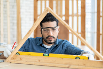 Carpenter working using precision level to measure of wood in the wood workshop. Male carpenter worker works at the carpentry shop