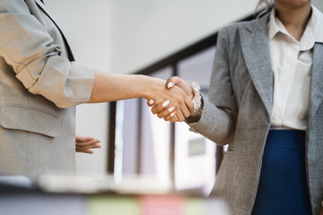 Fototapeta premium Businesswomen shake hands confidently at an office meeting.