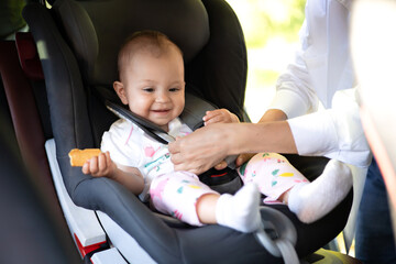 Traveling by car. A child in a car seat. Mom fastens the baby with seat belts. Holidays with...