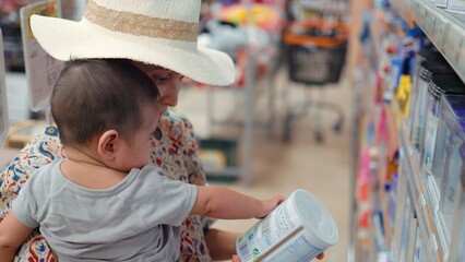 Young modern single mother choosing baby formula in supermarket