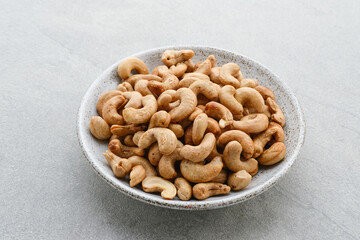 Cashew Nut, in Indonesia known as Kacang Mete. Served in a small bowl on grey background. 