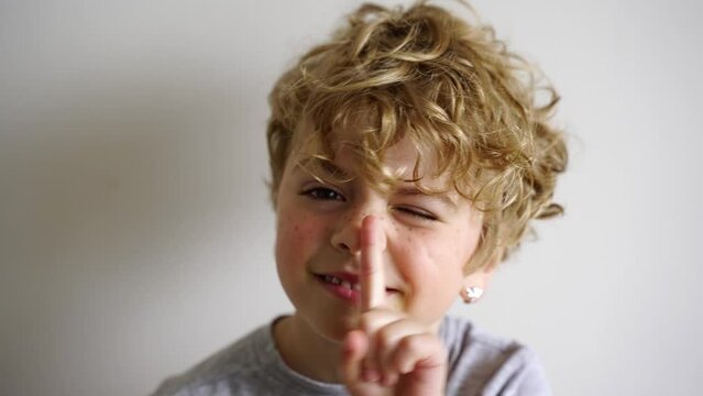 Portrait of a small cute curly funny blonde girl freckled face against a white background. Messing about. Caucasian with short haircut. Playful, naughty, make faces. 4K