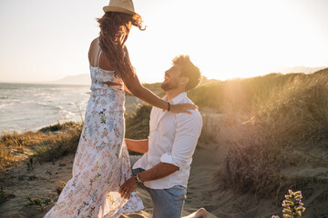 Boyfriend kneeling and making proposal to girlfriend on sunset beach