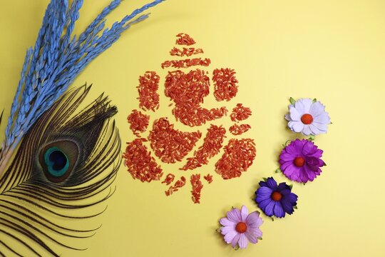  Ganesha art is made with colored rice. Ganesh Chaturthi wallpaper or banner. Ganpati face over yellow background along with diya and flowers. copy space.