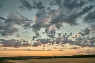 A harvested field in the evening against a cloudy after sunset sky.