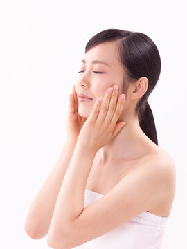 頬に手をそえスキンケアをする女性