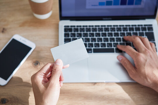 カードを持ちパソコンを操作する男性