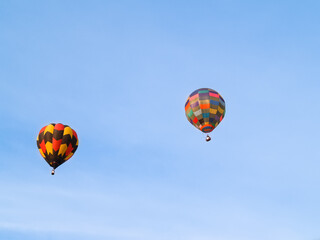Highly coloured hot air balloons high up in blue sky.