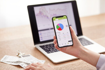 パソコンとスマートフォンでお金の管理をする女性