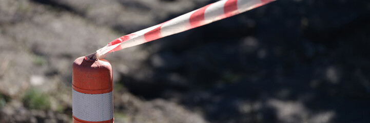 Red and white tape stretched in front of danger zone closeup
