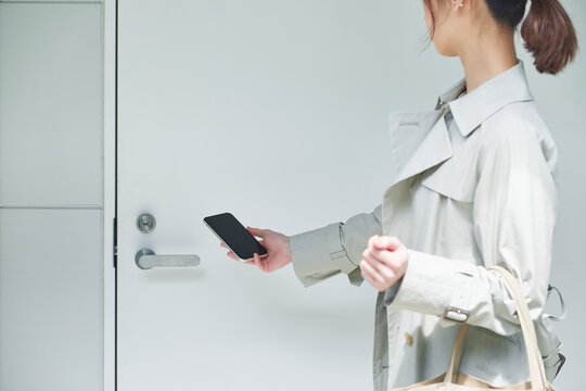 ドアにスマートフォンをかざす女性