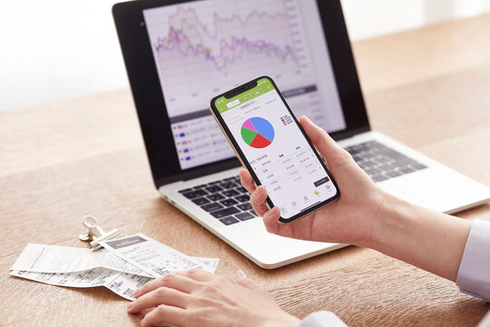 パソコンとスマートフォンでお金の管理をする女性