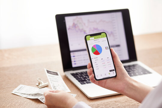 パソコンとスマートフォンでお金の管理をする女性