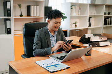  Young businessman Account Manager Working at Table with New Business Project. Typing smartphone ,Using Contemporary Laptop. Horizontal.