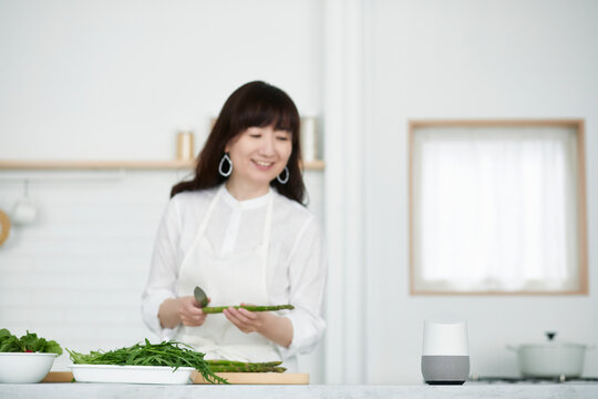 キッチンに立つ女性とスマートスピーカー