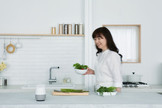 キッチンに立つ女性とスマートスピーカー