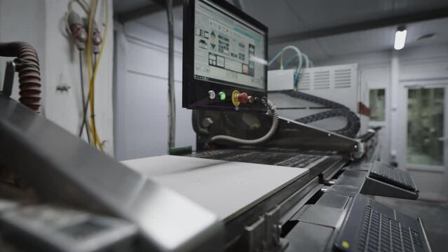 An industrial printer in a porcelain tile factory. The printer applies a pattern and texture to the board blank.