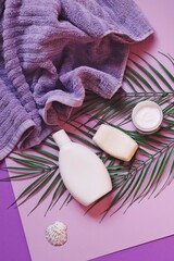 Obraz na płótnie Canvas Purple towel, shampoo bottle, moisturizing cream and natural soap top view photography. Bath products, toiletries set, spa cosmetics