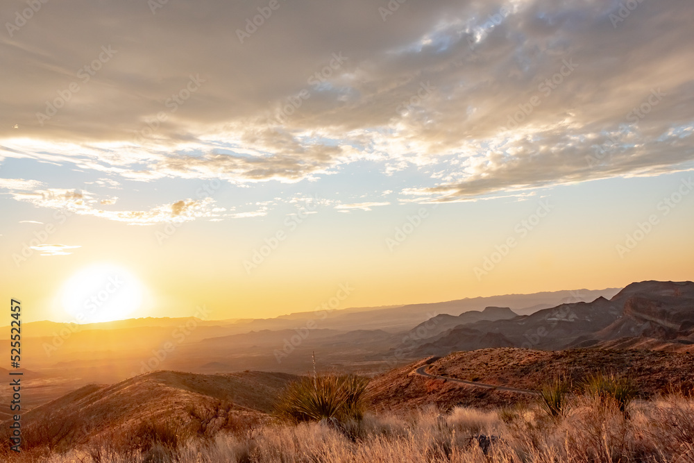 Wall mural dramatic golden sky sunset clouds over the grass fields and desert of big bend national park texas