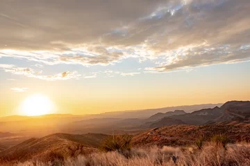 Fotobehang Pantone 2025 Mocha Mousse Dramatic golden sky sunset clouds over the grass fields and desert of Big Bend National Park Texas  © Jacki