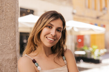 Cheerful young caucasian woman looking at camera, relaxing outdoors in city. Blonde beauty wears summer clothes. Lifestyle concept