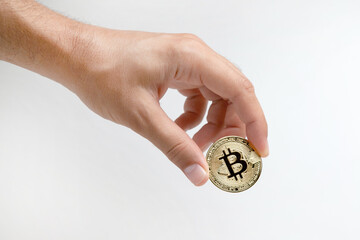 A man's hand holds a gold bitcoin, isolated on a white background