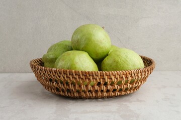 Crystal Guava (Psidium guajava) or Jambu Kristal, served in rattan basket on grey background, close up. 