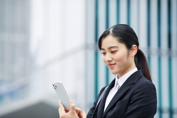 スマートフォンを持つスーツを着た笑顔の若い女性