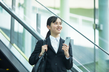 スーツを着てスマートフォンを持つ若い女性