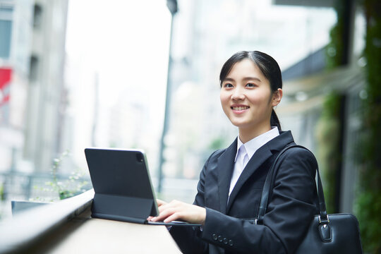 スーツを着てタブレット端末を操作する若い女性