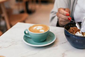 Two cups of flat white coffee on a marble table in a cafe. Eating a açai bowl for breakfast 