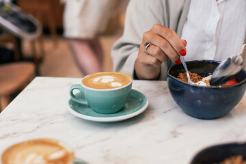 Two cups of flat white coffee on a marble table in a cafe. Eating a açai bowl for breakfast 